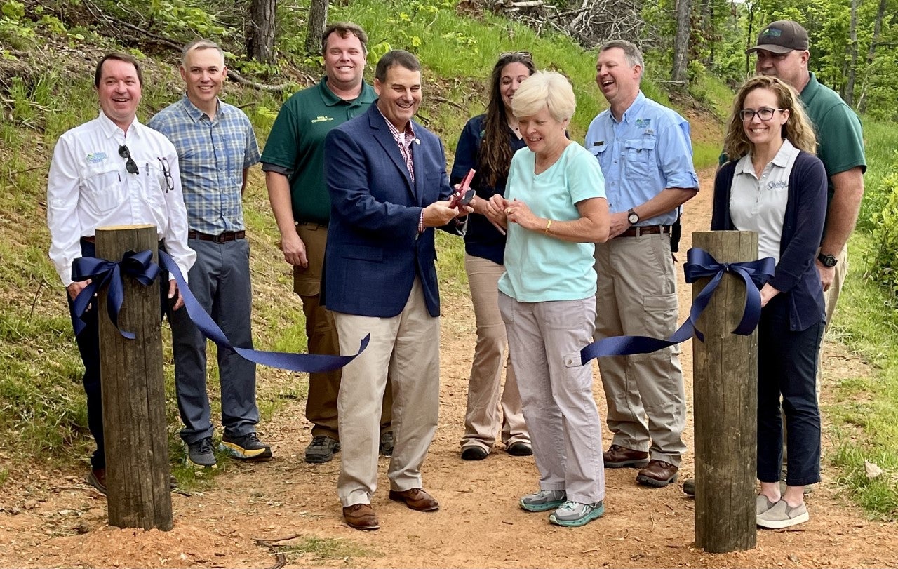 ADCNR Commissioner Chris Blankenship and Shelby County Commissioner Lindsey Allison cut the ceremonial ribbon for the new Lunker Lake Trail at Oak Mountain State Park on Friday, April 21, 2023 while joined by officials from Alabama State Parks and the Shelby County Commission. 